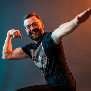 Studiossa kuvattu henkilökuva Ekhvan työntekijästä. Työntekijä nauraa ja poseeraa surffausasennossa.