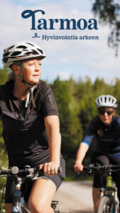 Nainen ja mies pyörilevät kesäisissä maisemissa pyöräilykypärät päässsään