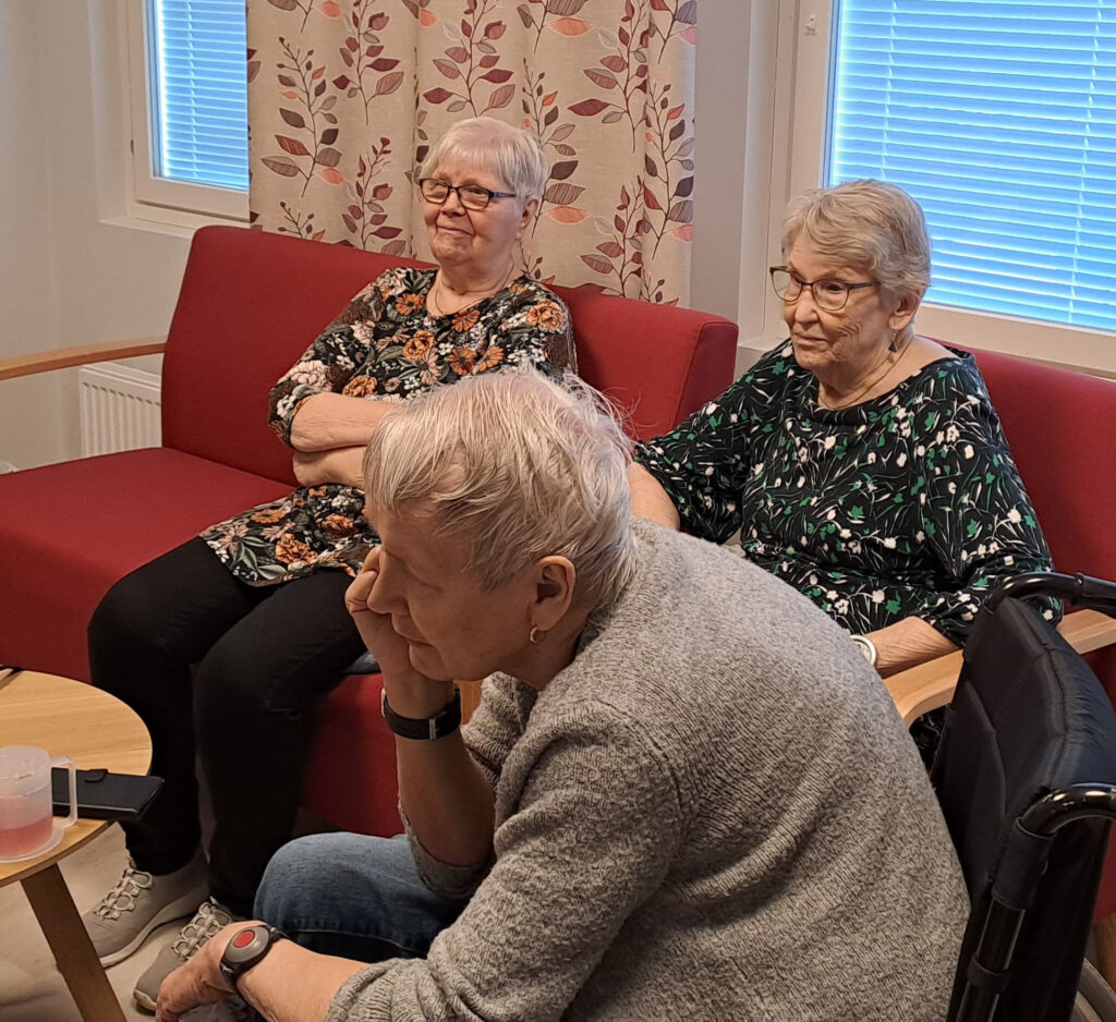Kolme rouvaa yhdessä istumassa ja juttelemassa keskenään.
