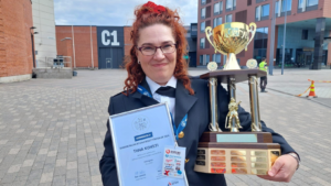 Tiina Konsti pokaalin ja kunniakirjan kanssa kuvattuna juhlapuvussa.