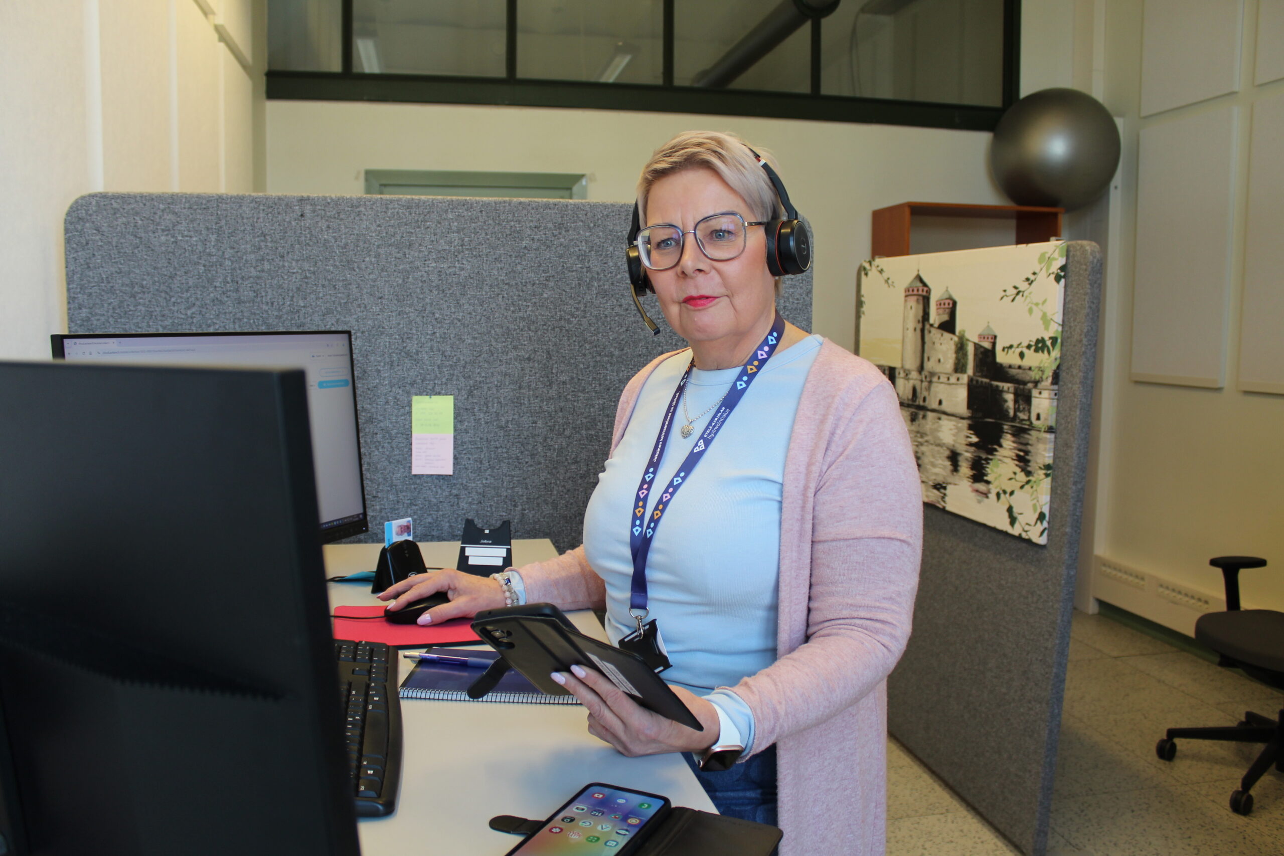 Lähihoitaja Anne katsoo työpisteensä äärestä kameraan.