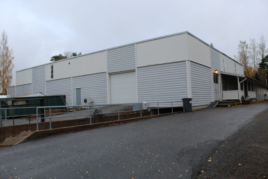 harmaa valkoinen rakennus, jossa liukuovi ja oikealla sivulla valkoinen ovi, jossa on valo yläpuolella palamassa