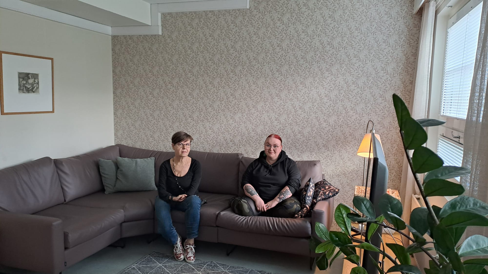 kaksi naista istuu sohvalla ja katsoo kameraan