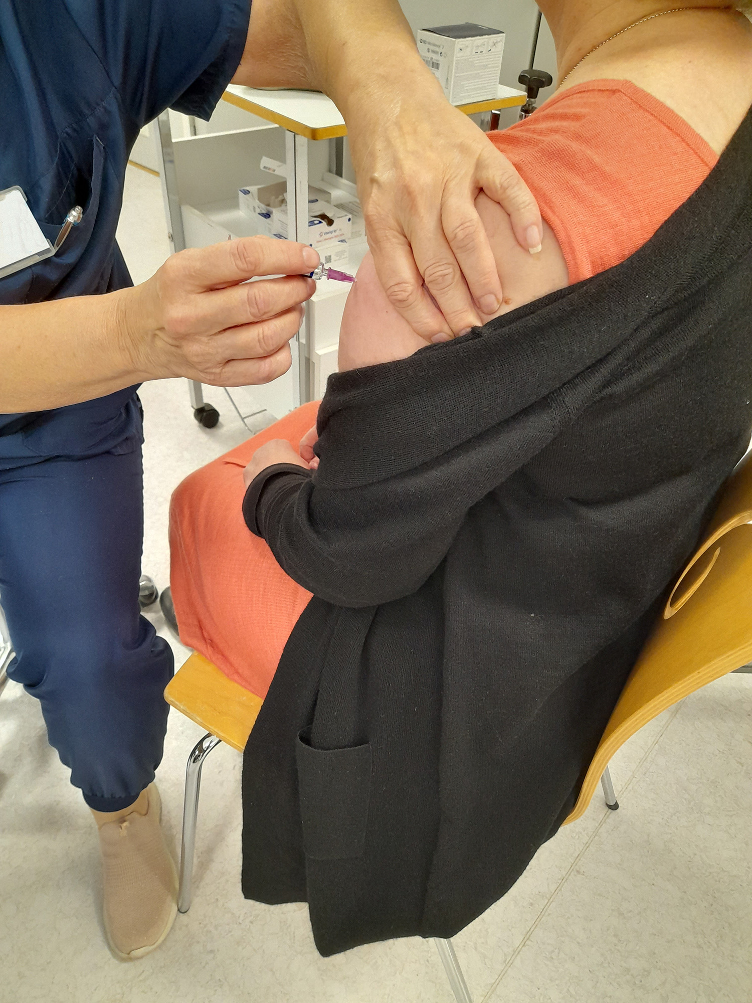 Rokotustilannekuva, kuvassa näkyy hoitajan käsi rokottamassa naishenkilöä.