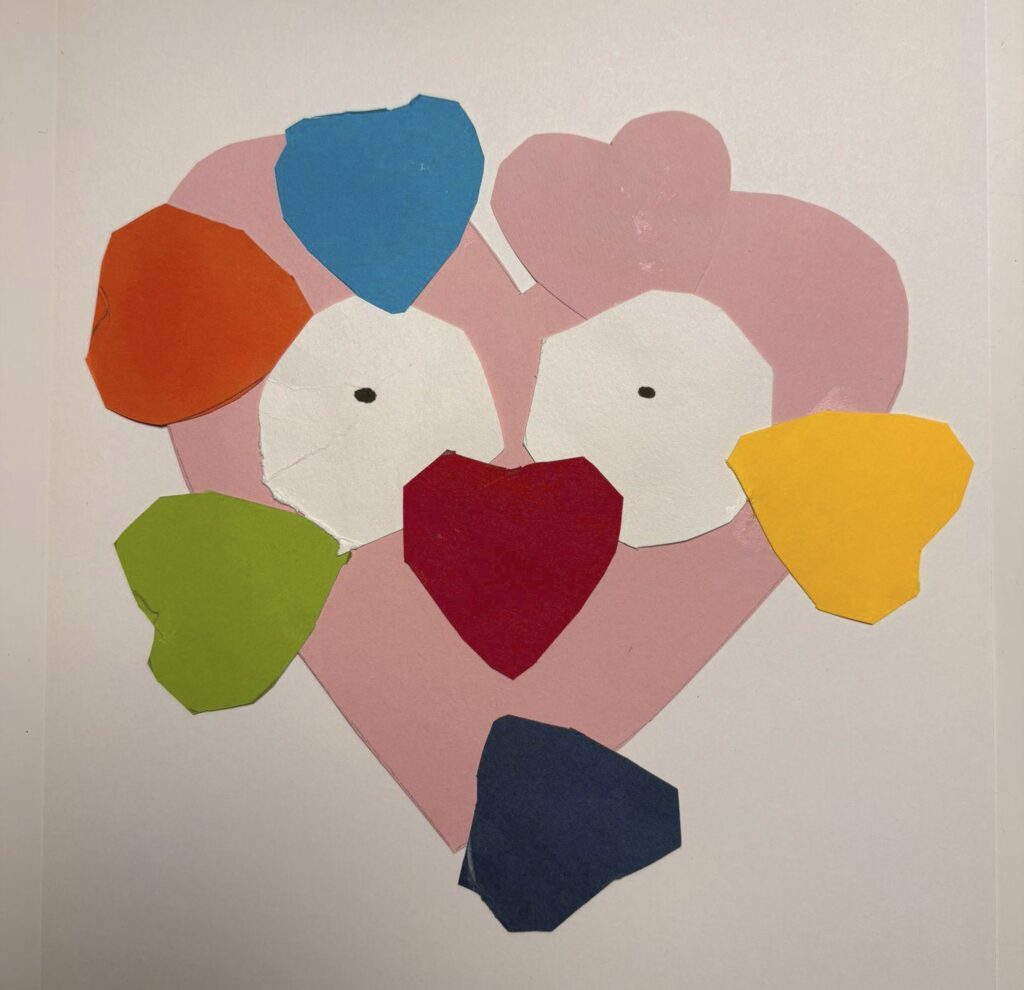 Värikäs lapsen tekemä askartelu, jossa on sydämen muotoinen vaaleanpunainen pää, jolla on silmät ja punainen sydännenä